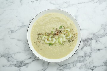 Bowl of delicious celery soup on white marble table, top view