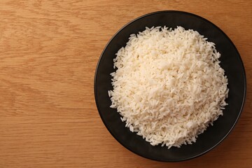 Plate with delicious rice on wooden table, top view. Space for text