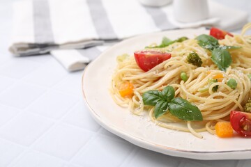 Delicious pasta primavera with tomatoes, basil and broccoli on white tiled table, closeup. Space for text