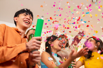 Group of Happy young Asian man and woman friends college student enjoy and fun celebration holiday event meeting party dancing and playing paper shoot together in living room at home on vacation night - obrazy, fototapety, plakaty