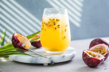 Glass of Iced passion fruit soda with lemon and passion fruit half slice on a light background, refreshing drink or beverage with ice