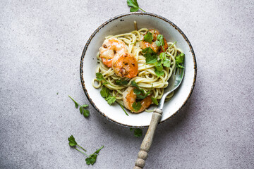 Several portions of cooked and twisted Spaghetti pasta with king prawn tails