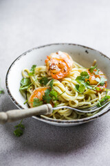 Several portions of cooked and twisted Spaghetti pasta with king prawn tails