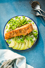 Poke bowl with rice, salmon,avocado and peas, sesame seeds on blue background