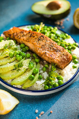 Poke bowl with rice, salmon,avocado and peas, sesame seeds on blue background