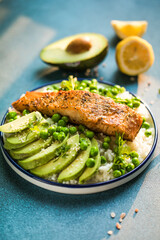 Poke bowl with rice, salmon,avocado and peas, sesame seeds on blue background