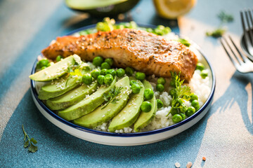 Poke bowl with rice, salmon,avocado and peas, sesame seeds on blue background