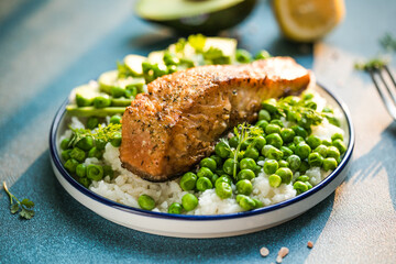 Poke bowl with rice, salmon,avocado and peas, sesame seeds on blue background