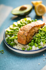 Poke bowl with rice, salmon,avocado and peas, sesame seeds on blue background