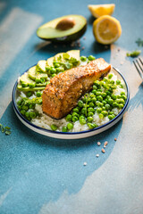 Poke bowl with rice, salmon,avocado and peas, sesame seeds on blue background