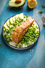 Poke bowl with rice, salmon,avocado and peas, sesame seeds on blue background