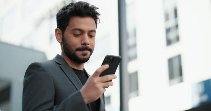 Handsome young businessman smiling while using a smartphone