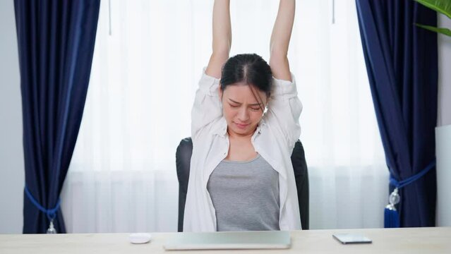 Office syndrome concept. Young asian woman feeling pain in neck and shoulder after working on computer laptop for a long time. She stretches to relax her muscles