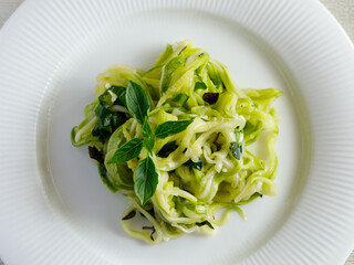 Salad of marinated raw zucchini spaghetti in spices and herbs. Vegan food. Healthy meal. Top view, close up