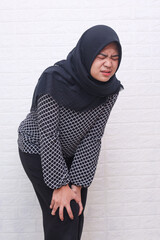 Asian muslim woman suffering from knee or leg pain over white background.