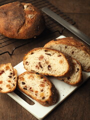 slice of raisin, cranberry and perilla seed bread on white cutting board on wood