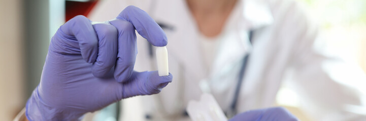 Doctor proctologist holding in his hands antiinflammatory suppository for hemorrhoids closeup