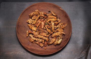 pile of spicy fried meatball snacks cut into ovals on a brown wooden plate