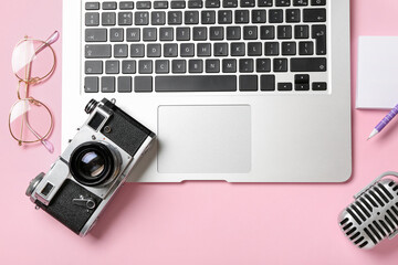Laptop with photo camera, eyeglasses and microphone on pink background
