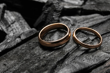 Golden wedding rings on black charcoal, closeup