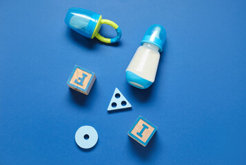 Bottle of milk for baby and accessories on blue background
