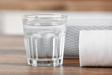 Glass of water with filters on wooden table in kitchen