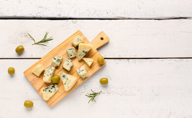 Fototapeta na wymiar Board with pieces of tasty cheese on light wooden background