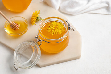 Board, jars and bowl with dandelion honey on white background