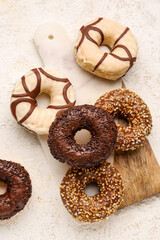 Board with sweet chocolate donuts on light grunge background