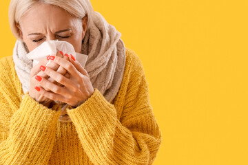 Ill mature woman with tissue on yellow background