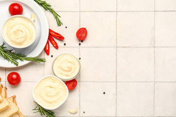 Bowls of tasty cream cheese on white tile background