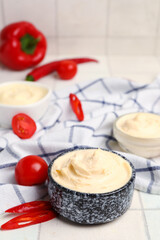 Bowl of tasty cream cheese on white tile background