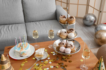 Tray with confectionery, Birthday cake and party decor on table in living room