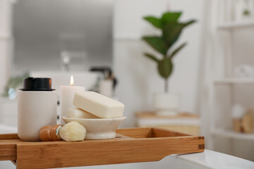 Fototapeta na wymiar Shaving brush, soap bars and bath accessories on board in interior of bathroom, closeup