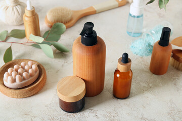 Bottles of cosmetic products, massage soap and cream on light background