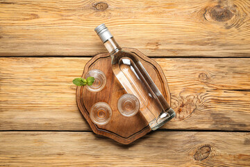 Bottle and glasses of vodka on wooden background - obrazy, fototapety, plakaty