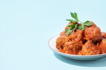 Plate of tasty meat balls with sauce on blue background