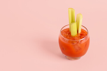 Glass of bloody mary with celery on pink background