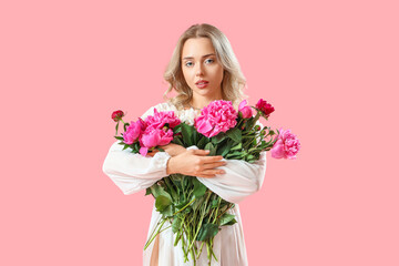 Young woman with beautiful peony flowers on pink background