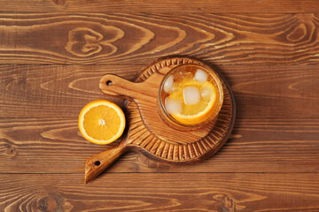 Boards with glass of ice tea and orange on wooden background