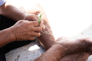 The man is repairing a fishing net on a boat in a village, Indonesia