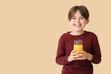 Little boy with glass of orange juice on beige background