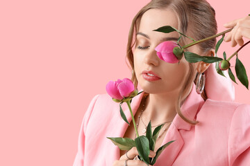 Beautiful young woman with peony flowers on pink background