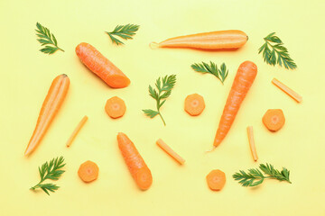 Fresh carrots and slices on yellow background