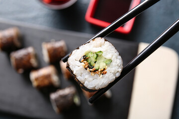 Chopsticks with tasty maki roll, closeup view © Pixel-Shot