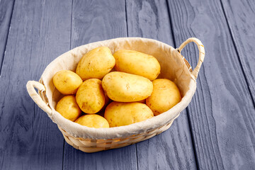 Wicker basket with raw baby potatoes on blue wooden background