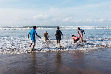 Happy latin friends teenagers at beach party runs and jumping to pacific ocean in Acapulco Mexico...