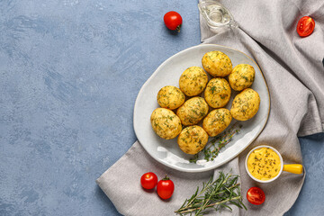 Plate of boiled baby potatoes with dill and tomatoes on blue background