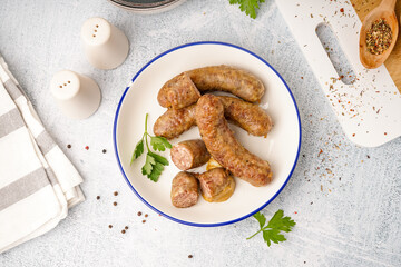 Plate of tasty homemade sausages on light background