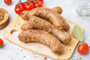 Wooden board of tasty homemade sausages on light background